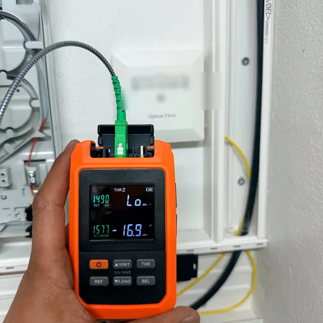 Photomètre optique en main mesurant la puissance sur une prise fibre OTO